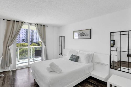 een witte slaapkamer met een bed en een groot raam bij Ocean reserve On the Beach Best Location in Miami Beach