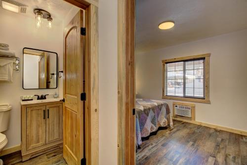 um quarto com uma cama, um lavatório e um espelho em Alpine Lodge Hotel em Cascade