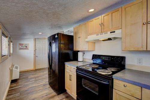 a kitchen with a black refrigerator and wooden cabinets at Alpine Lodge Hotel in Cascade