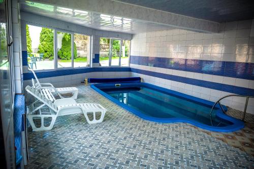 - une piscine avec 2 chaises et une balançoire dans l'établissement Pensiunea Larisa, à Ocna Şugatag