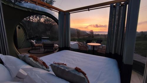 Ce lit se trouve dans un dortoir offrant une vue sur le coucher du soleil. dans l'établissement Luzada - Glamping Burbujas Galicia, à Juances