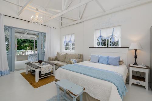 a white bedroom with a bed and a couch at Golf Beach and Sea in Southbroom