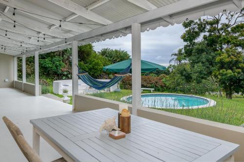 un patio con una mesa, una hamaca y una piscina en Golf Beach and Sea en Southbroom