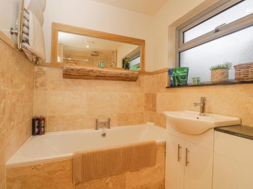 a bathroom with a tub and a sink and a mirror at Little Foxes in Calne