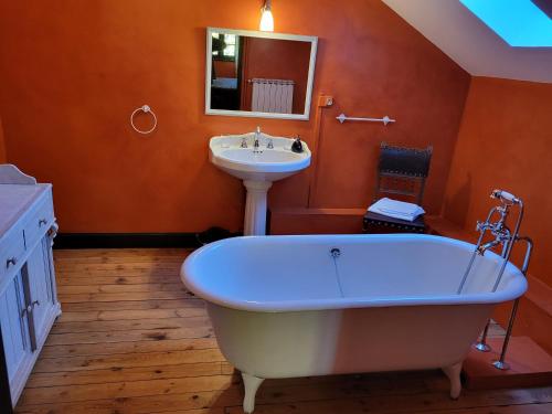 a bathroom with a white tub and a sink at Le Temps des Cerises in Génolhac