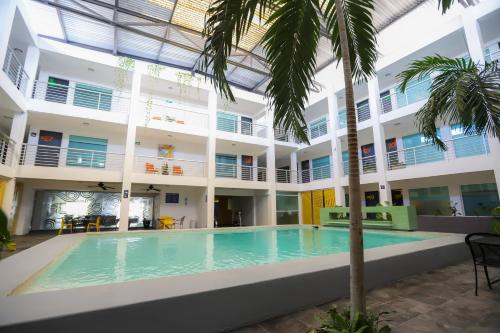 uma piscina interior num edifício com uma palmeira em TRYP by Wyndham Chetumal em Chetumal