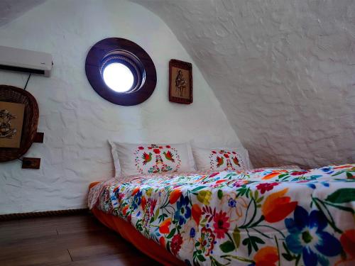 1 dormitorio con 1 cama con colcha de flores y ventana en Căsuțele de sub Șipote en Porumbacu de Sus