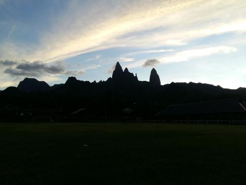 a sunset with mountains in the background with a field at Chez Laeti et Mano in Hakamui
