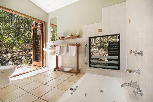 ein Bad mit einer Badewanne und einem Fenster in der Unterkunft Lyola Pavilions in the Forest in Maleny