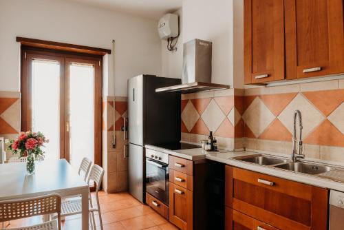 uma cozinha com um lavatório, um frigorífico e uma mesa em LA CASA DI ALICE 2 em Lido di Ostia