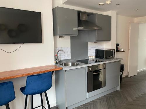 a kitchen with a sink and a counter with blue bar stools at Stunning apartment in the heart of Leeds in Leeds