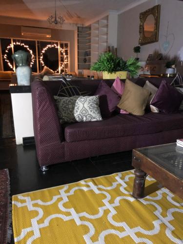 a living room with a purple couch with pillows on it at Muco Guest House in Johannesburg