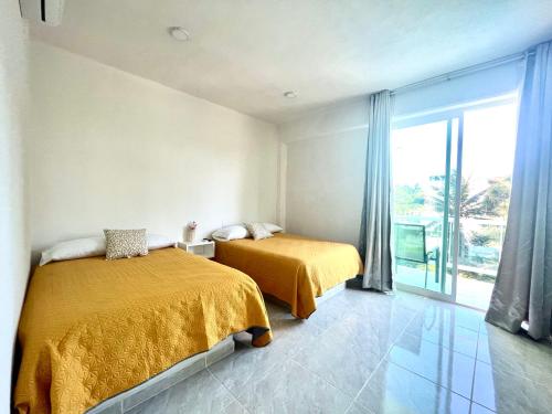 a bedroom with two beds and a large window at Gran Palma Residencial in Acapulco
