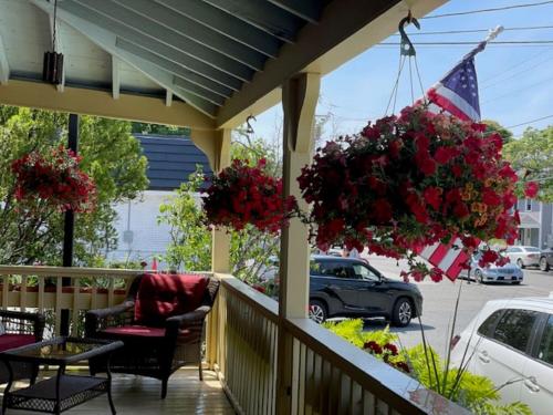 a porch with flowers and an american flag at Central House Inn in Bar Harbor