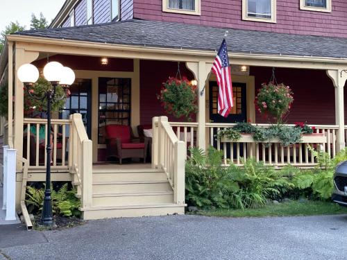 a house with a porch with a flag on it at Central House Inn in Bar Harbor
