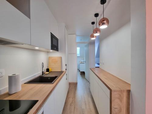 une cuisine avec des armoires blanches et un comptoir en bois dans l'établissement Travel Homes - NewGate 3, elegant, heart of Colmar, à Colmar