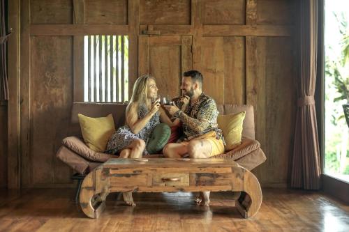 a man and a woman sitting on a couch at Masakali Retreat in Ubud