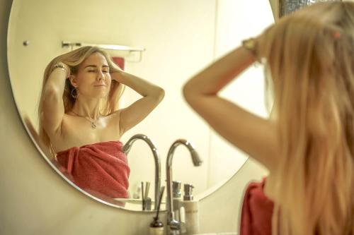 a woman brushing her hair in front of a bathroom mirror at Masakali Retreat in Ubud