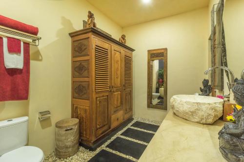 a bathroom with a large wooden cabinet and a tub at Masakali Retreat in Ubud