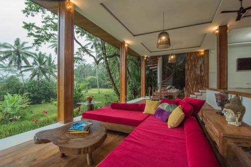 a living room with a red couch and a large window at Masakali Retreat in Ubud