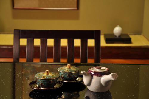 a tea pot and three cups on a glass table at Arima Gyoen in Kobe