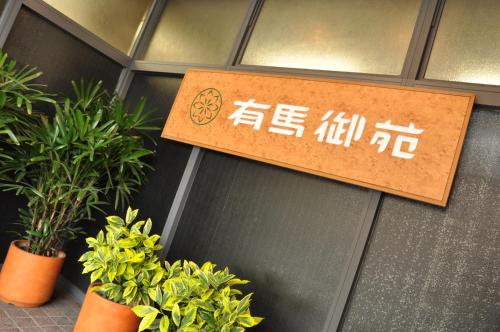 a sign on the side of a building with plants at Arima Gyoen in Kobe