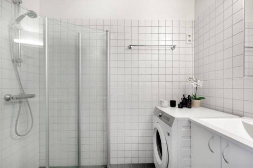 a white bathroom with a shower and a washing machine at Tjuvholmen - ved Aker Brygge in Oslo
