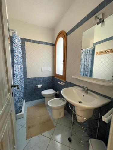 a bathroom with a sink and a toilet and a mirror at Casa delle Farfalle in Chia