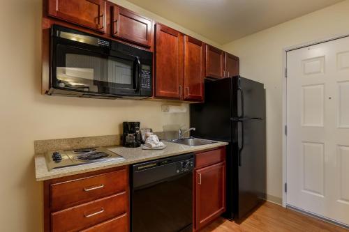 a kitchen with a black refrigerator and a sink at MainStay Suites Fitchburg - Madison in Madison