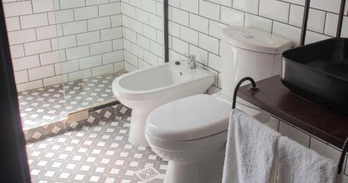 a white bathroom with a toilet and a sink at Monte Refugio Urbano in San Salvador de Jujuy