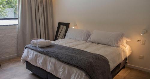 1 dormitorio con 1 cama con sábanas blancas y ventana en Monte Refugio Urbano en San Salvador de Jujuy