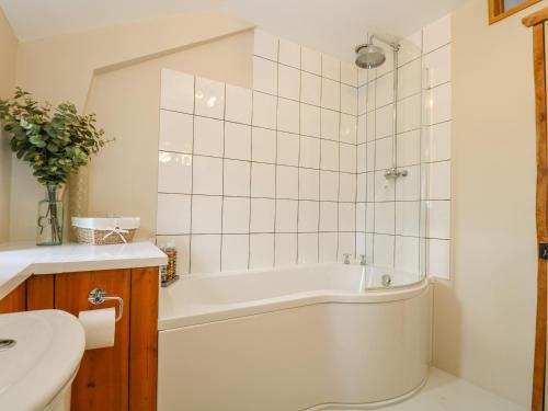 a white bathroom with a tub and a sink at Woodfield Coach House in Merrymeet