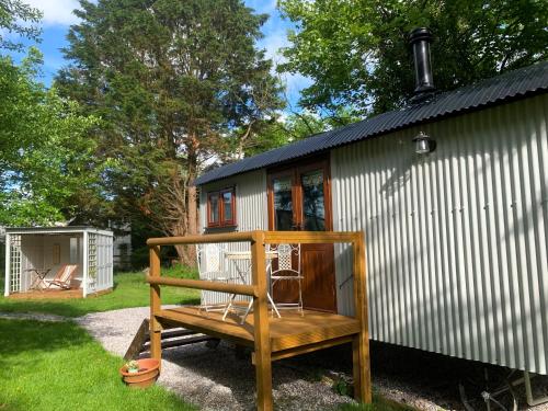 een klein huis met een bankje ervoor bij Lilliput - Delightful 1-bedroom shepherd's hut in Holsworthy