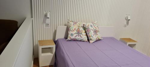 een kleine slaapkamer met een paars bed met een kussen bij Victoria Studio in Vilamoura