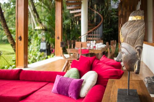 a couch with red pillows on a patio at Masakali Retreat in Ubud