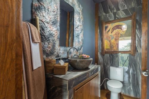 a bathroom with a bowl sink and a toilet at Masakali Retreat in Ubud
