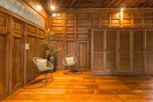 two chairs in a room with wooden walls at Masakali Retreat in Ubud