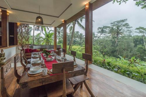 a dining table in a room with a view of the forest at Masakali Retreat in Ubud