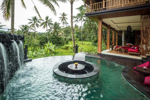 a pool in the middle of a house with a waterfall at Masakali Retreat in Ubud