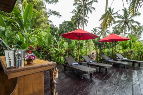 a group of benches with red umbrellas on a deck at Masakali Retreat in Ubud
