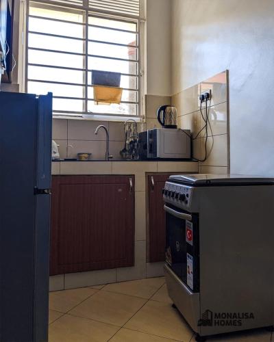 Il comprend une cuisine équipée d'une cuisinière et d'un évier. dans l'établissement Green mona unit, à Kampala