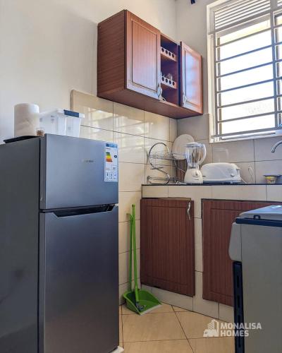 une cuisine avec un réfrigérateur en acier inoxydable et un aspirateur dans l'établissement Green mona unit, à Kampala