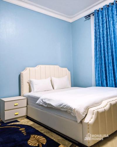 een blauwe slaapkamer met een bed en een raam bij Green mona unit in Kampala