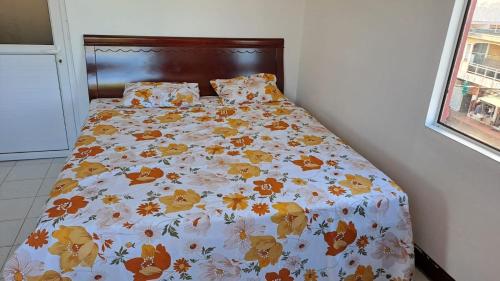 Una cama con una manta con flores. en Chez Bibi, 