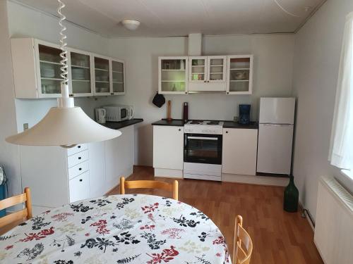 a kitchen with a table and a kitchen with white cabinets at Feriestedet Skovly in Klemensker