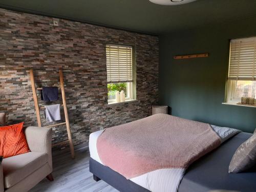 a bedroom with a bed and a chair at Secret Wellness Boszicht in Holten