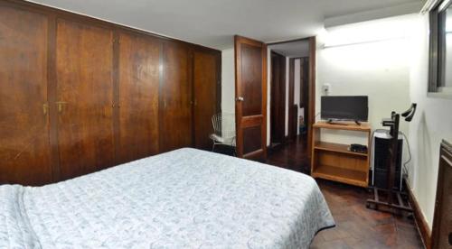 1 dormitorio con 1 cama blanca y TV en Silencioso con patio en Buenos Aires