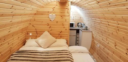 a small room with a bed in a wooden wall at Loughmourne Glamping Pod 