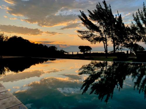 a pool of water with a sunset in the background at Lagoon Suites e Gastronomia in Laguna
