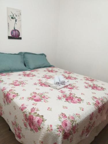 Una cama con una manta floral y un teléfono. en Kitnet espaçosa e bem localizada - Próximo ao lago e centro de eventos en Cascavel